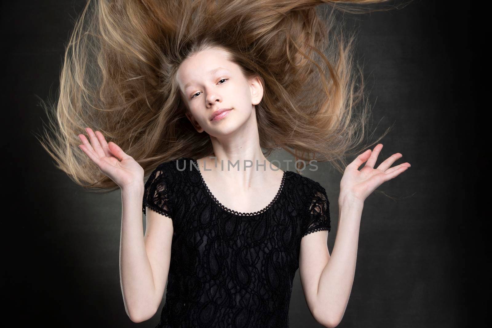 Beautiful teenager girl with flowing hair on a gray background.