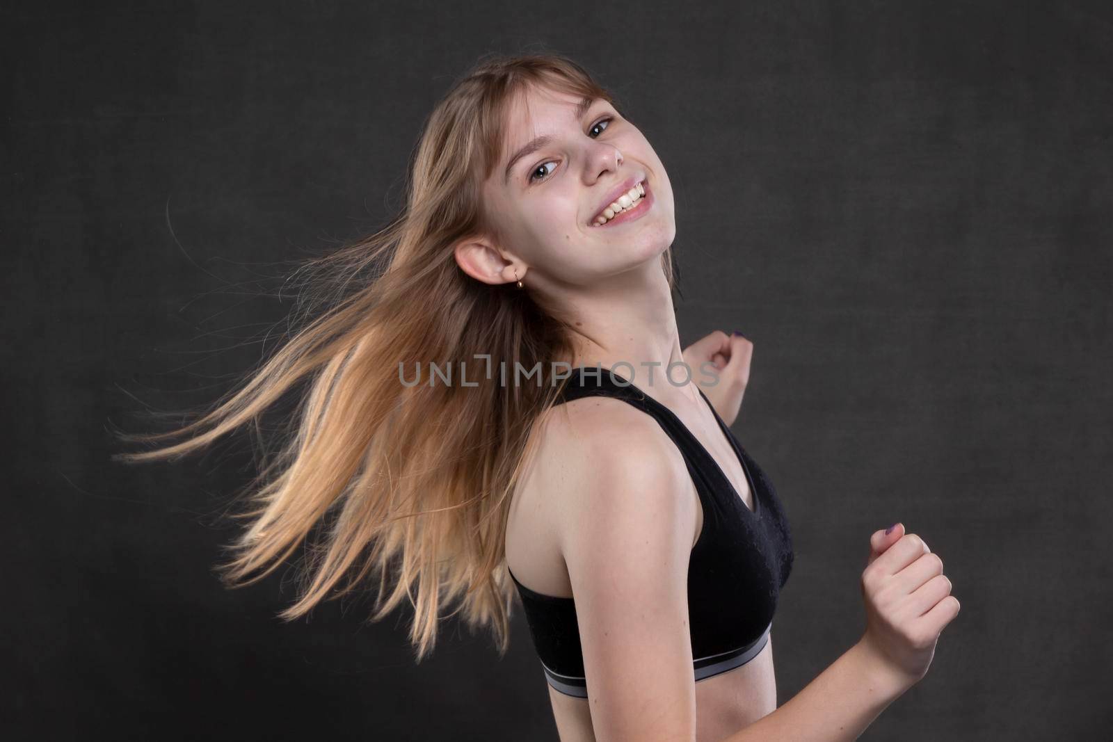 Beautiful teenager girl with developing hair on a dark background.