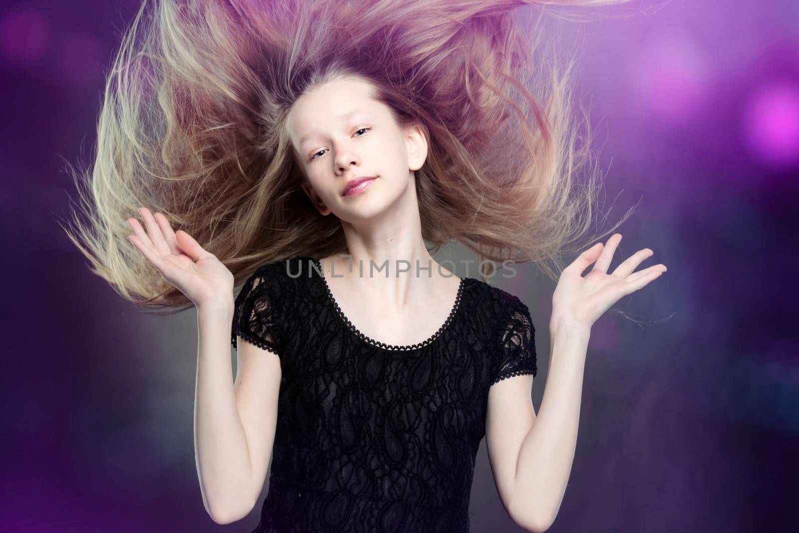 Against a purple background, a beautiful teenage girl flapped her hair.