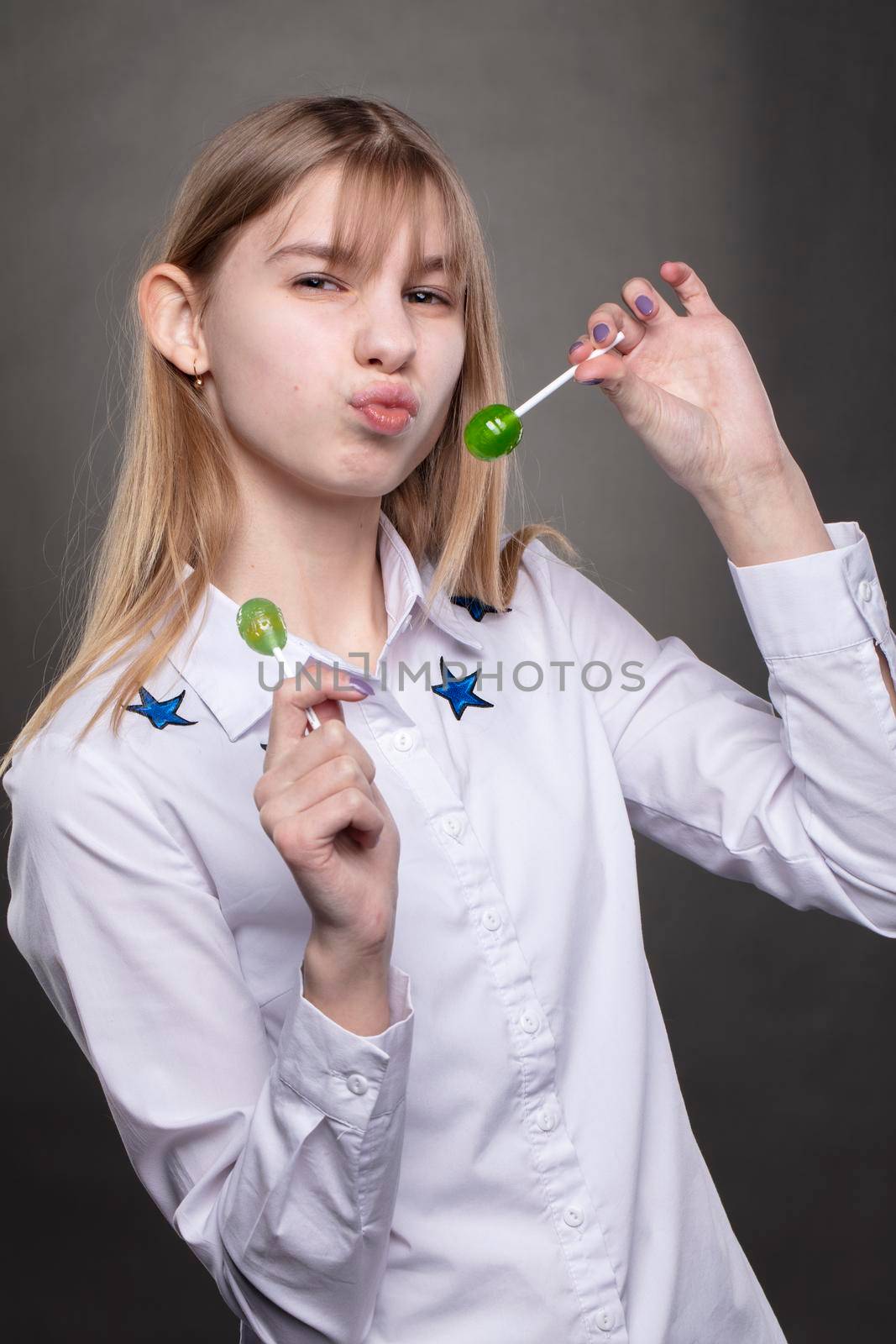 A funny and naughty teenager girl with a lollipop fooling around at the camera.