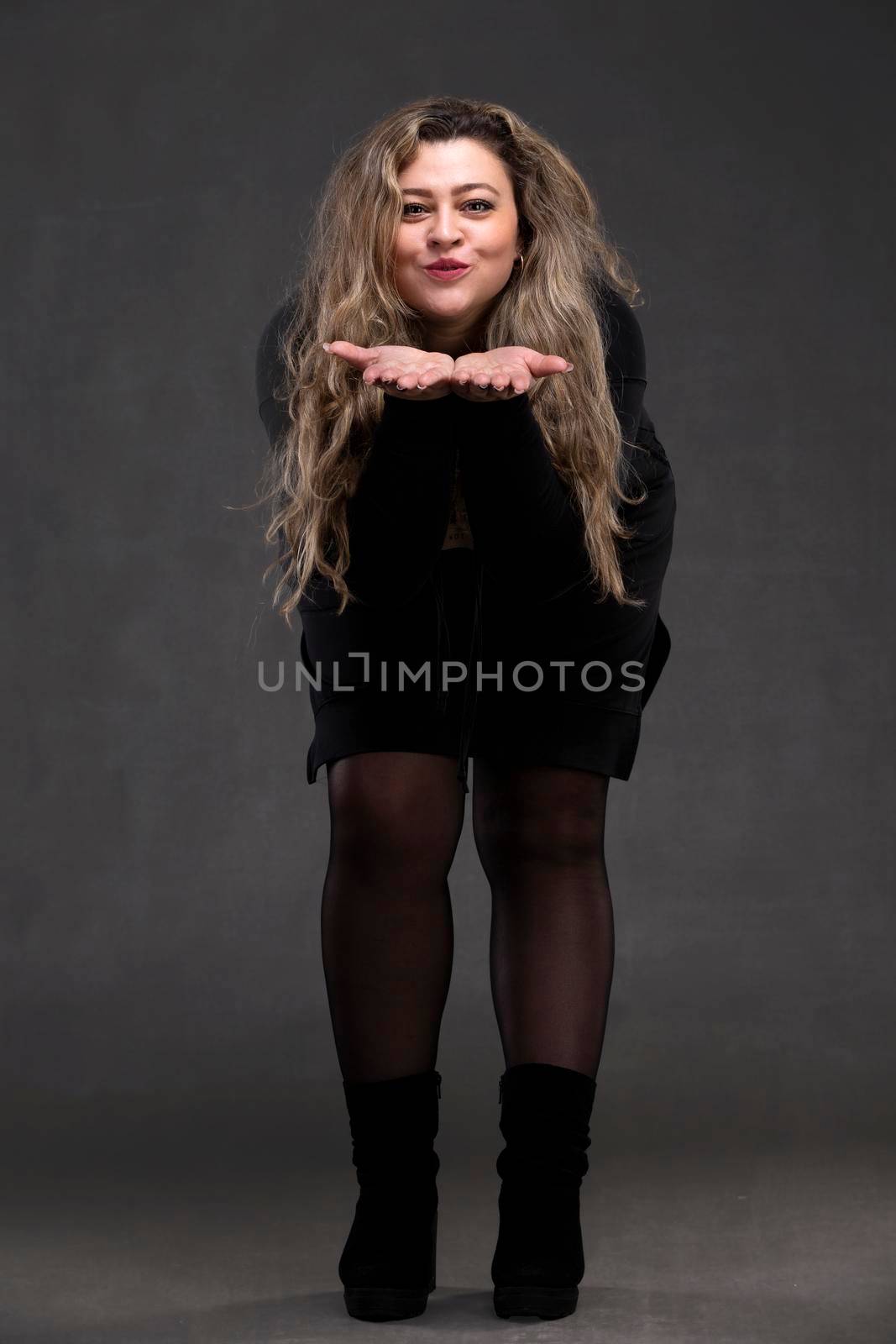 Beautiful fat woman with long curly hair and black dress blowing on her arms.