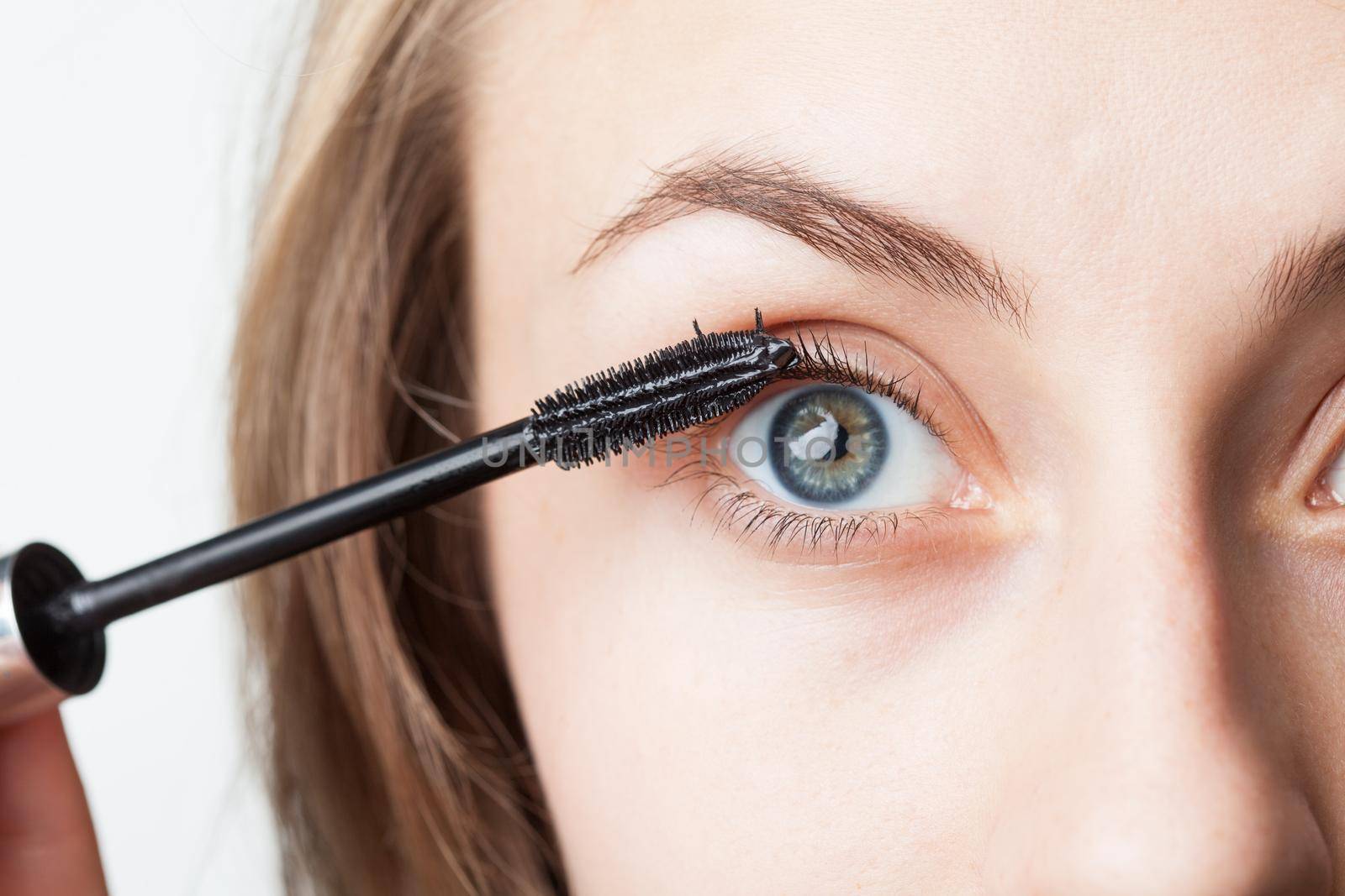 Woman applying mascara on her eyelashes