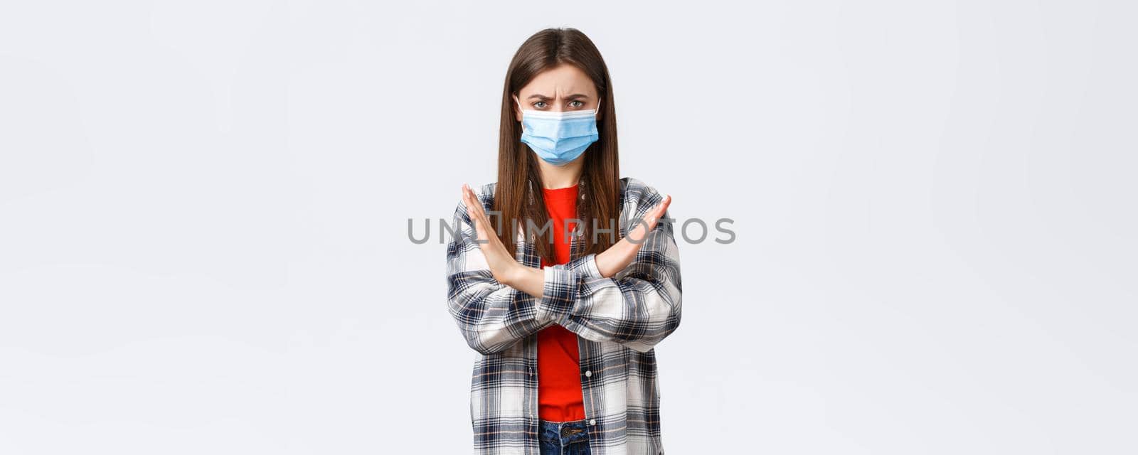 Coronavirus outbreak, leisure on quarantine, social distancing and emotions concept. Enough, this should stop. Serious displeased young woman in medical mask protest, show cross sign.