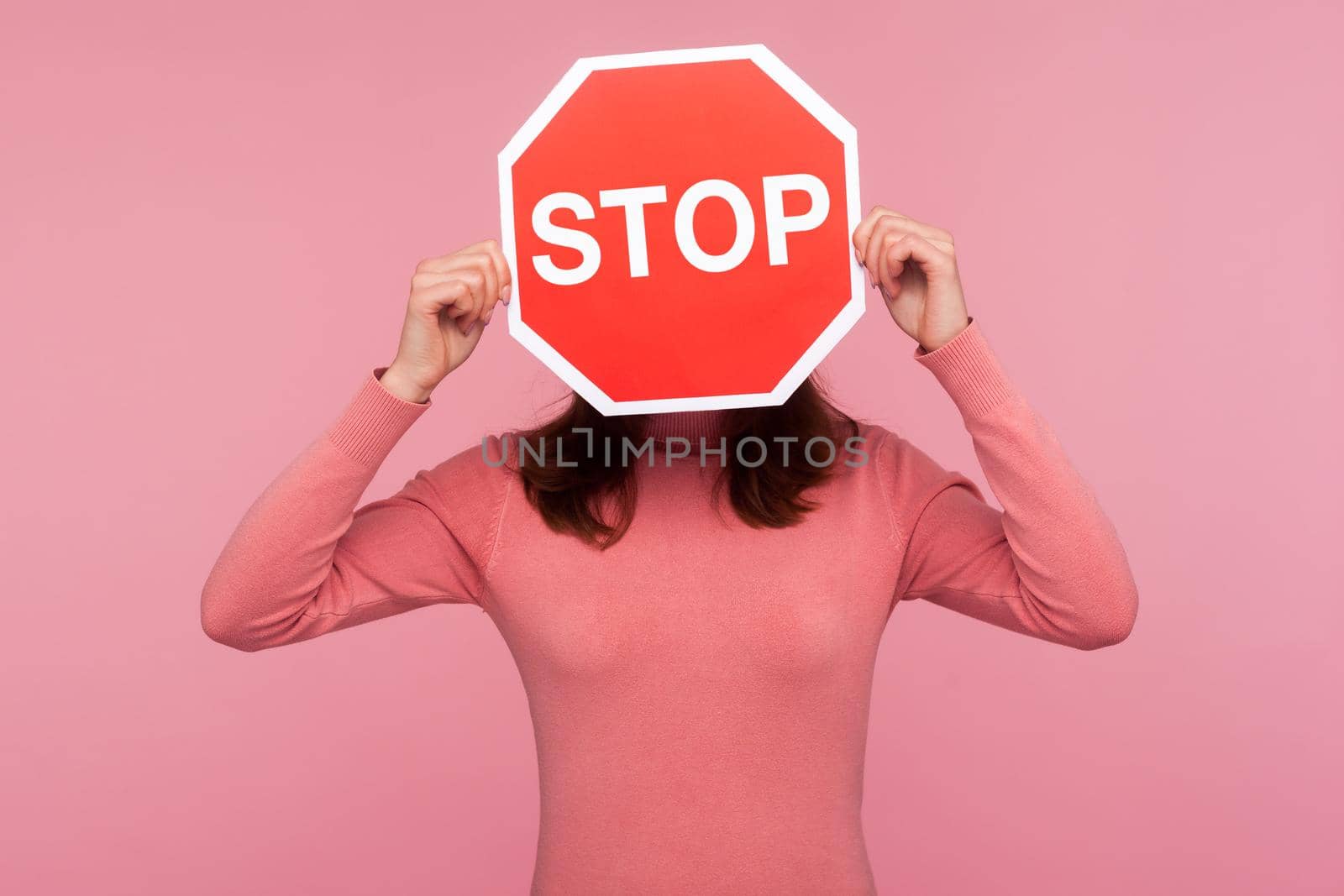 Brunette woman in pink sweater hiding face behind stop sign, way prohibited by Khosro1