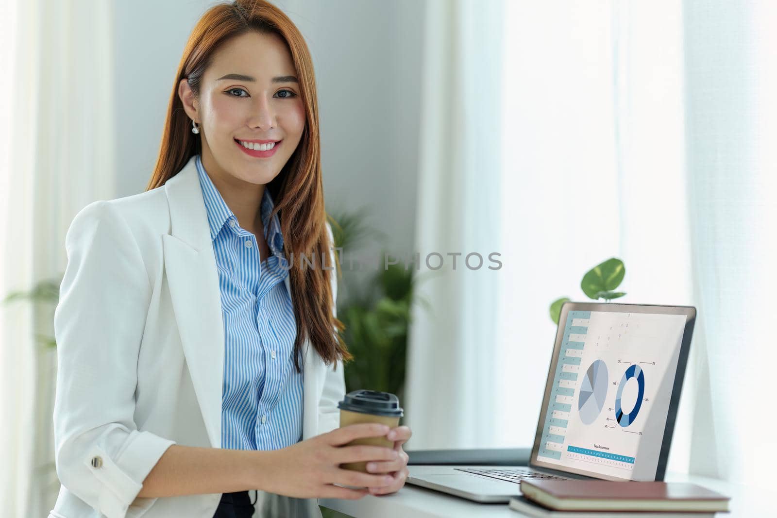 Portrait of an Asian business woman sitting at work and using a computer labtop in the office by Manastrong