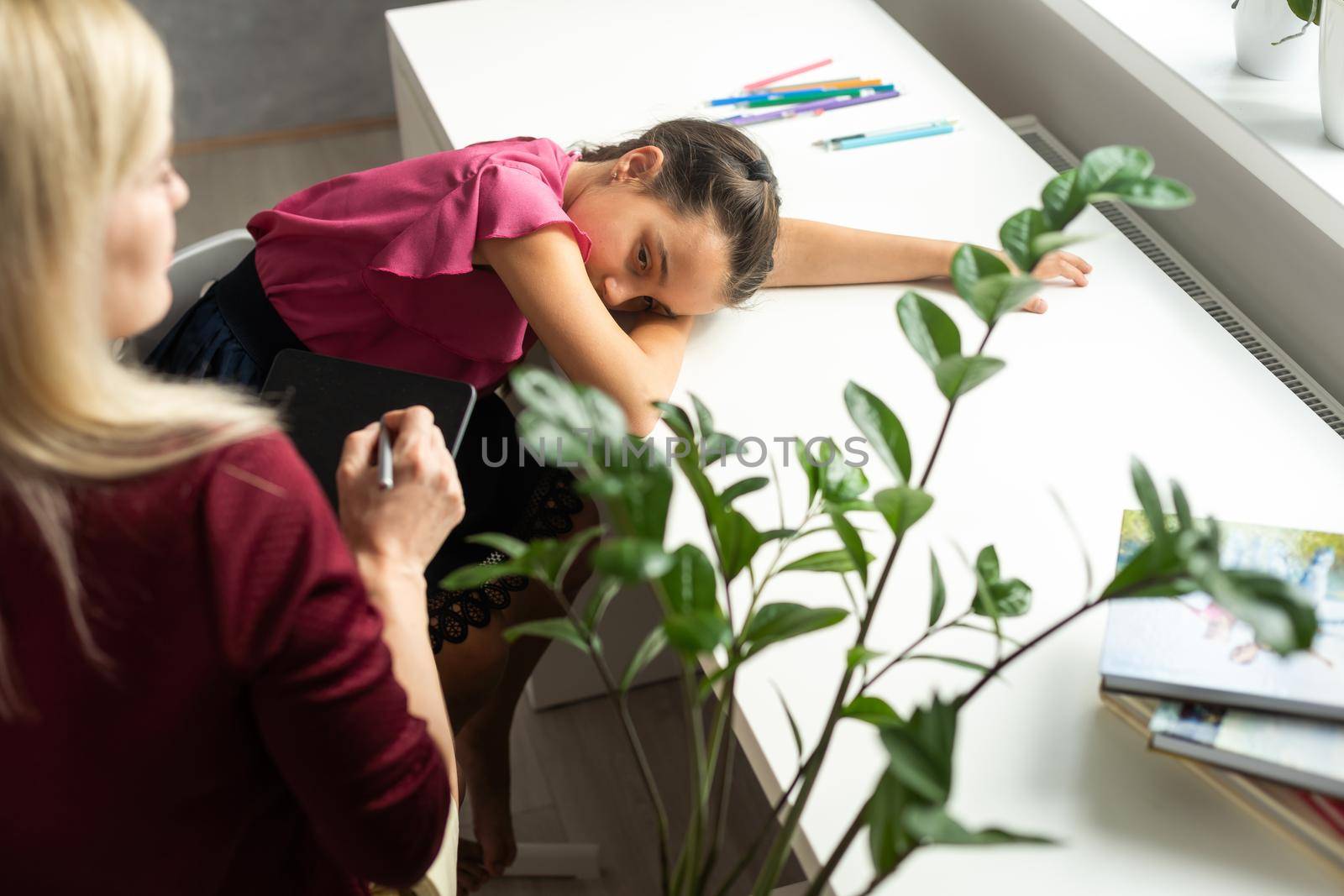 Female psychologist working with little girl at home.