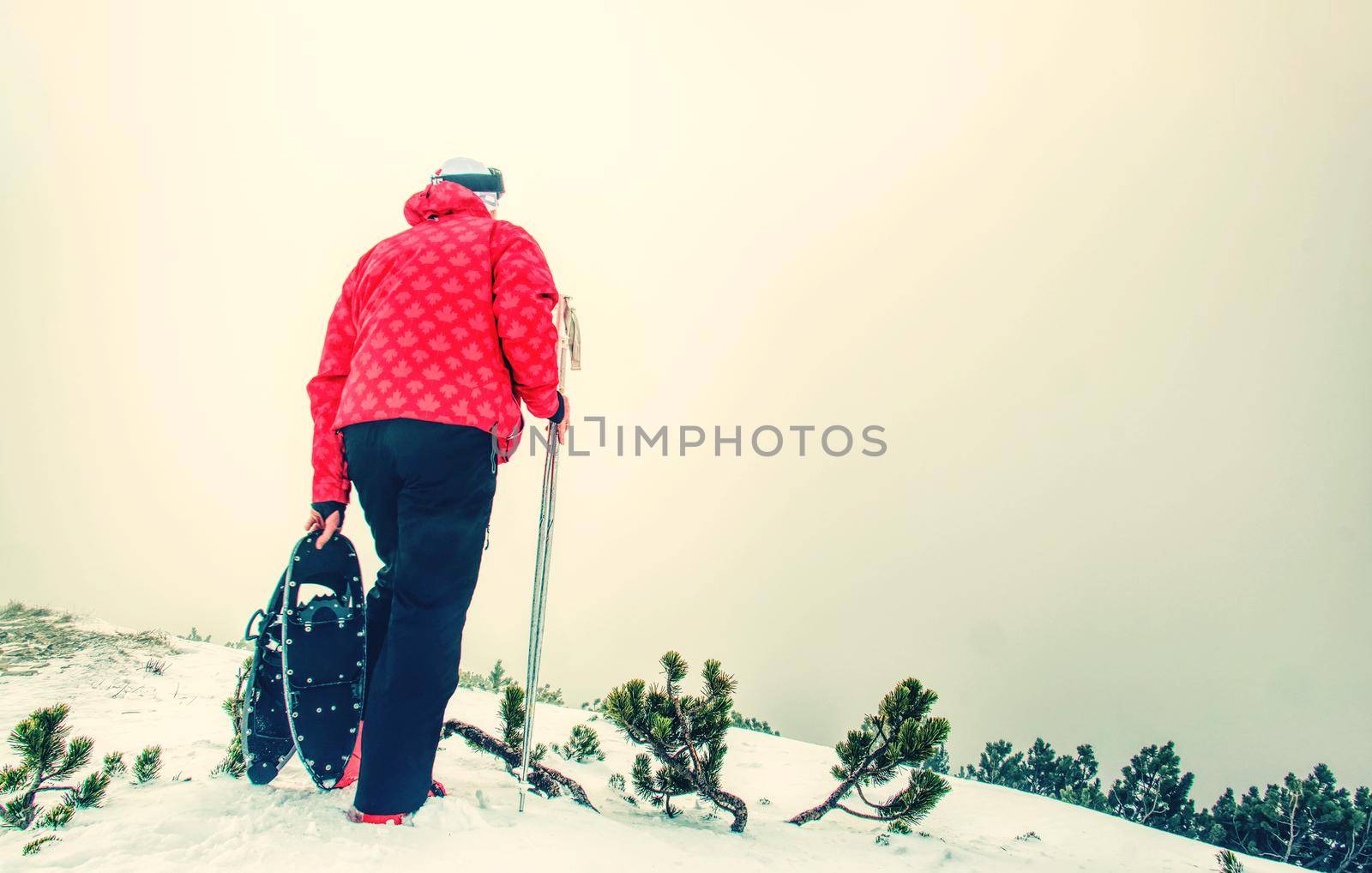 Man with snowshoe on the snow path. Man in snowshoes with trekking poles is the snow in the mountains.