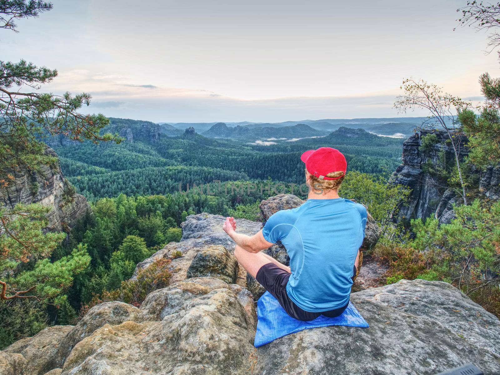 Man meditates in yoga position in mountains above wild nature at sunset. Concept of meditation, spirituality and  soul balance