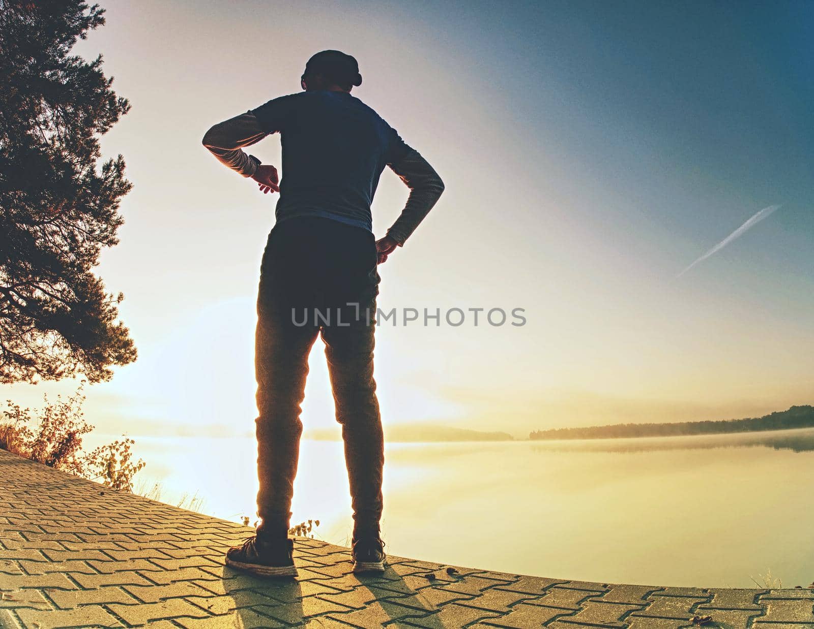 Runner tired exhausted during cardio effort using his wearable technology smartwatch checking heart rate monitor. Outdoor run at lake