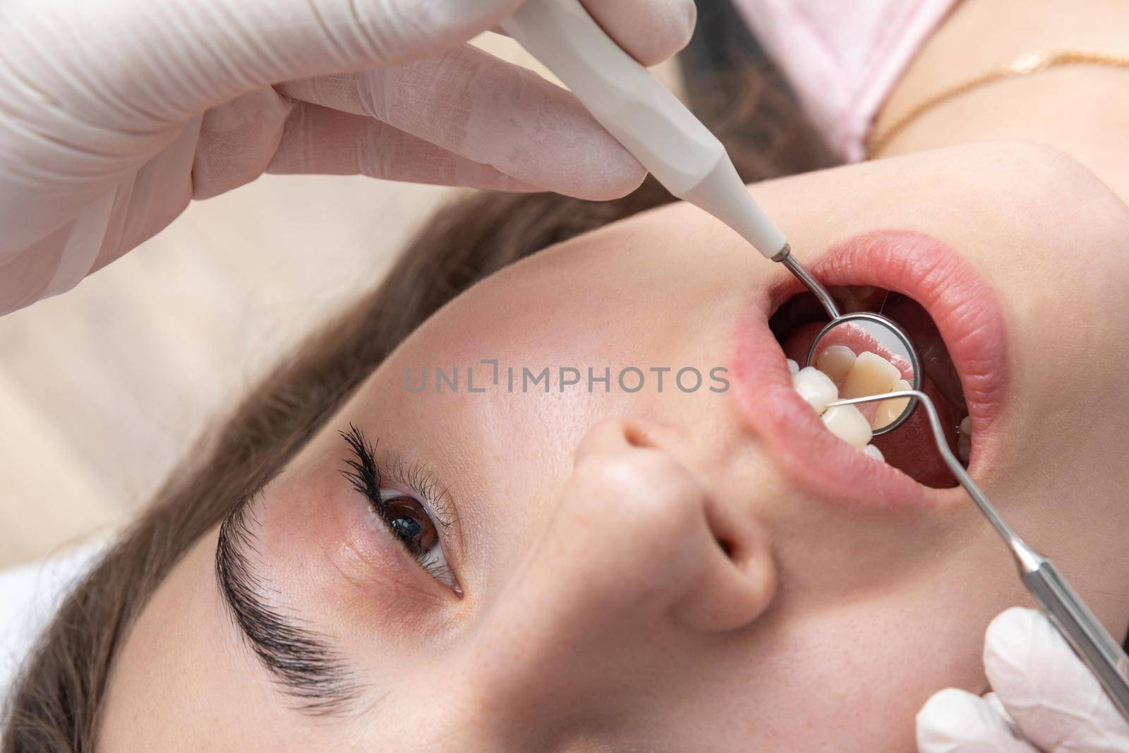Dentist examining patient teeth with dental mirror during dental check up by Mariakray