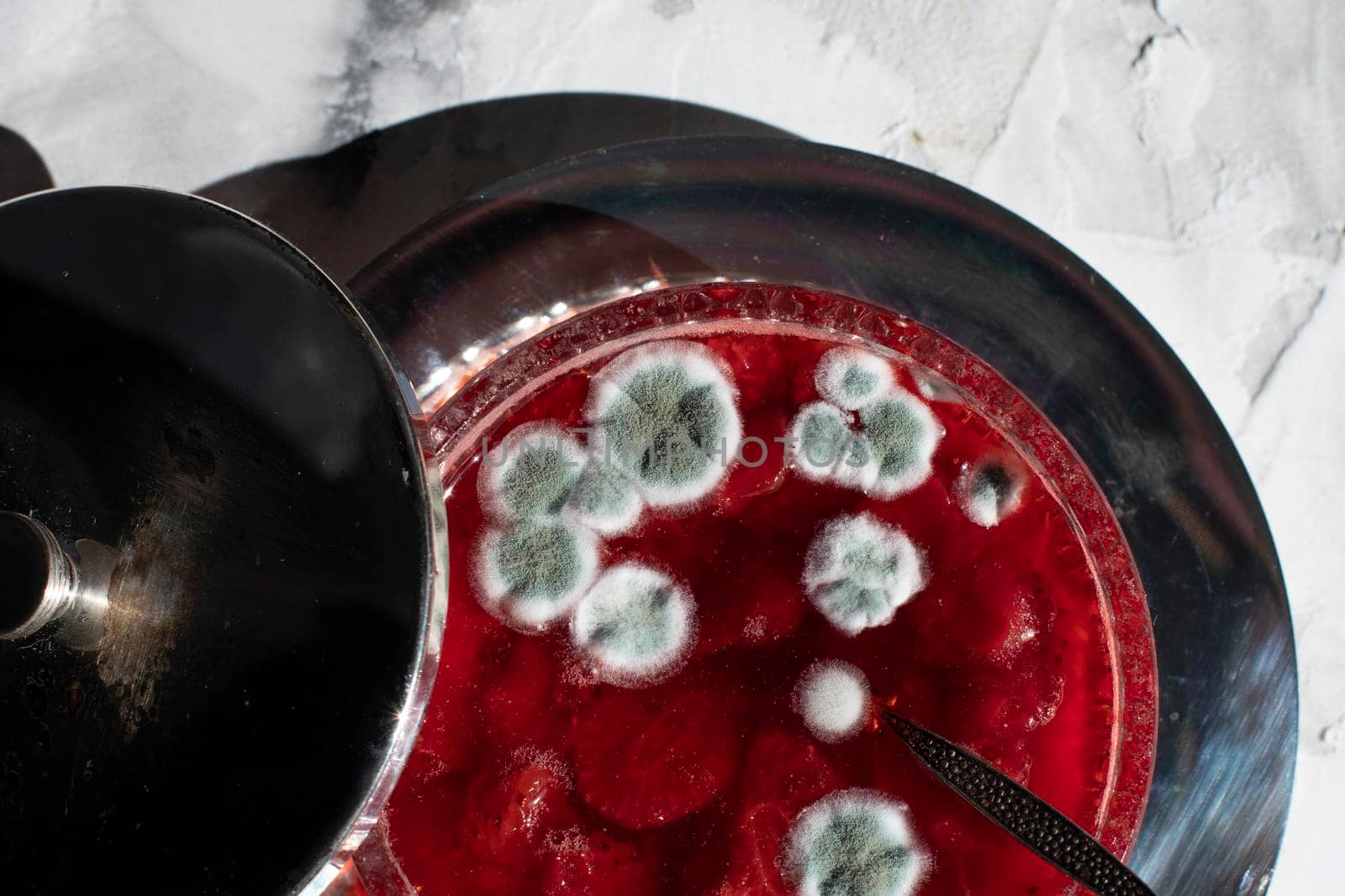 blue mold on strawberry jam, violation of cooking technology, health hazard, spoiled product, beautiful blue spots on a red background. High quality photo