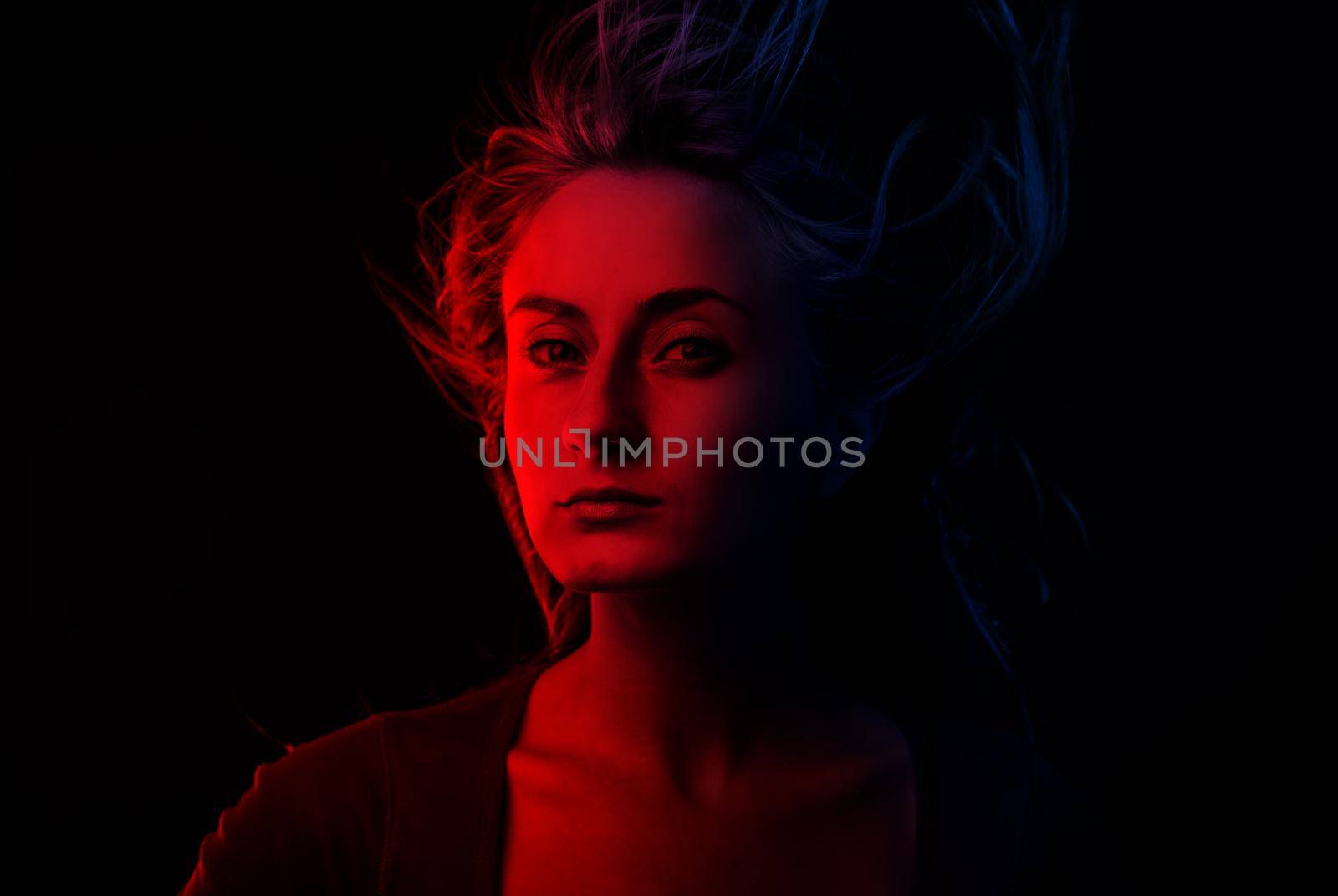 Studio romantic portrait of a young woman in dark red and blue tonality