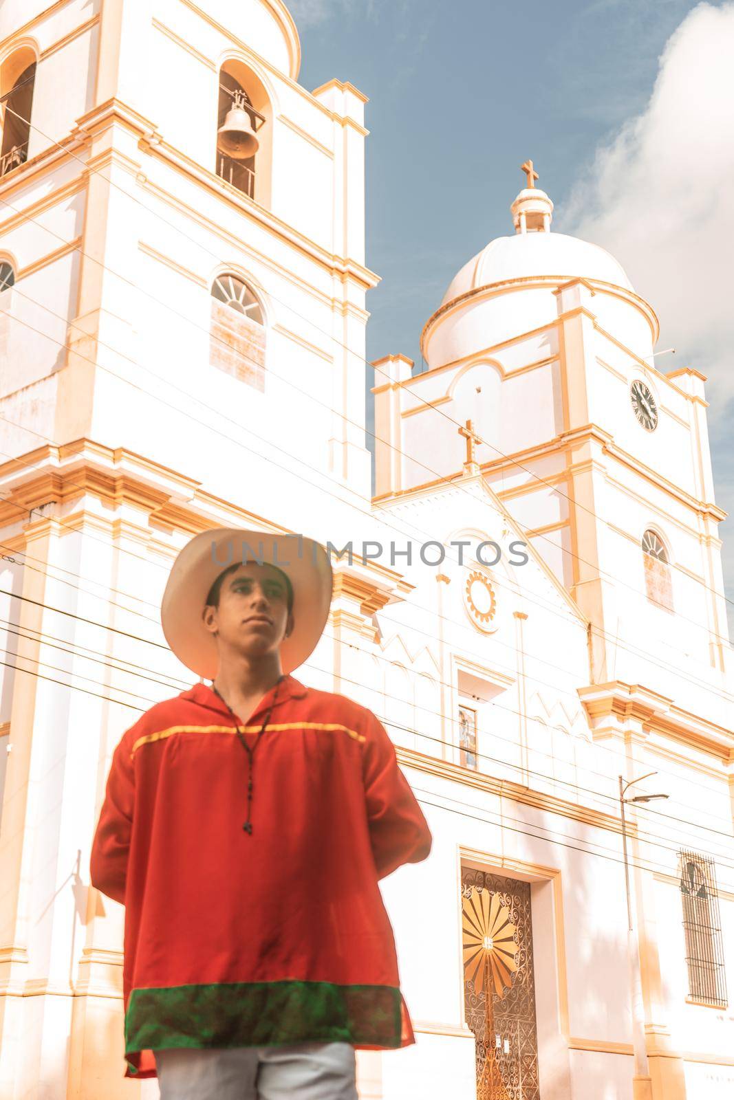 Latin teenager with classic clothes and hat from Nicaragua and the traditional dance from Latin America in front of the cathedral church of Jinotega
