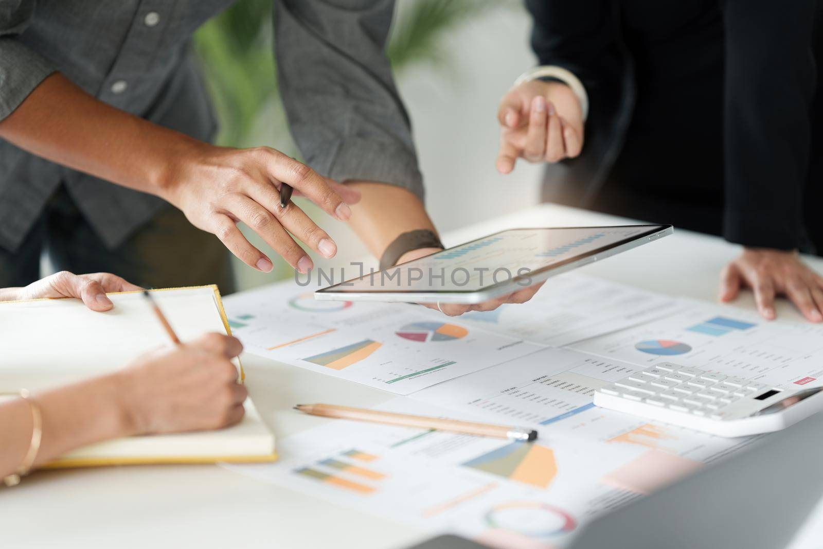 Group of business people working at workplace. Business team hands at working with financial plan, meeting, discussion, brainstorm with tablet on office desk