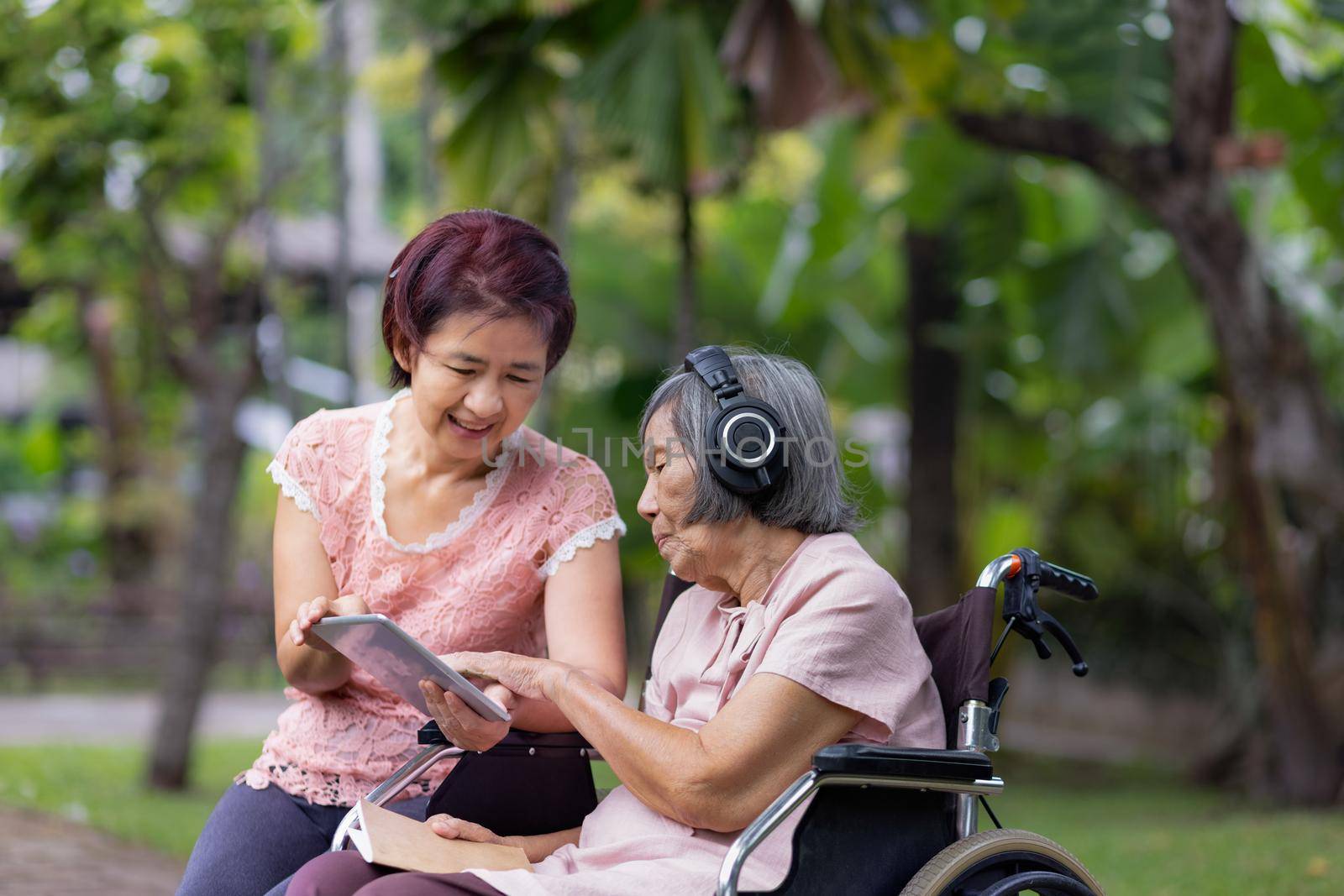 senior woman and daughter listening music with headphone in backyard