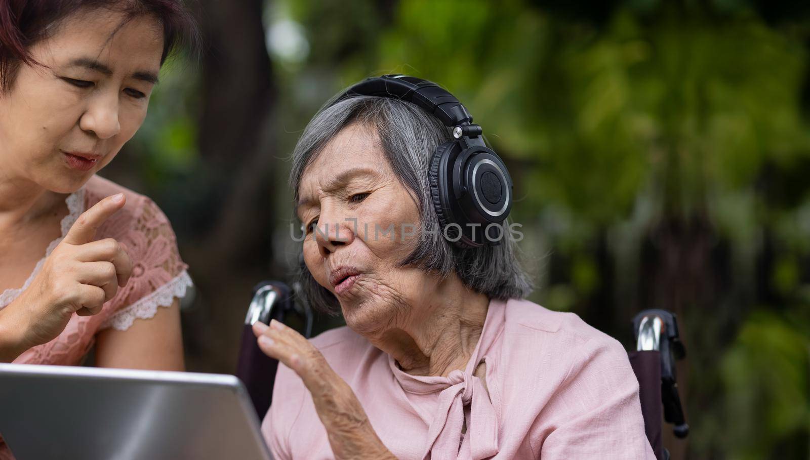 senior woman and daughter listening music with headphone in backyard by toa55
