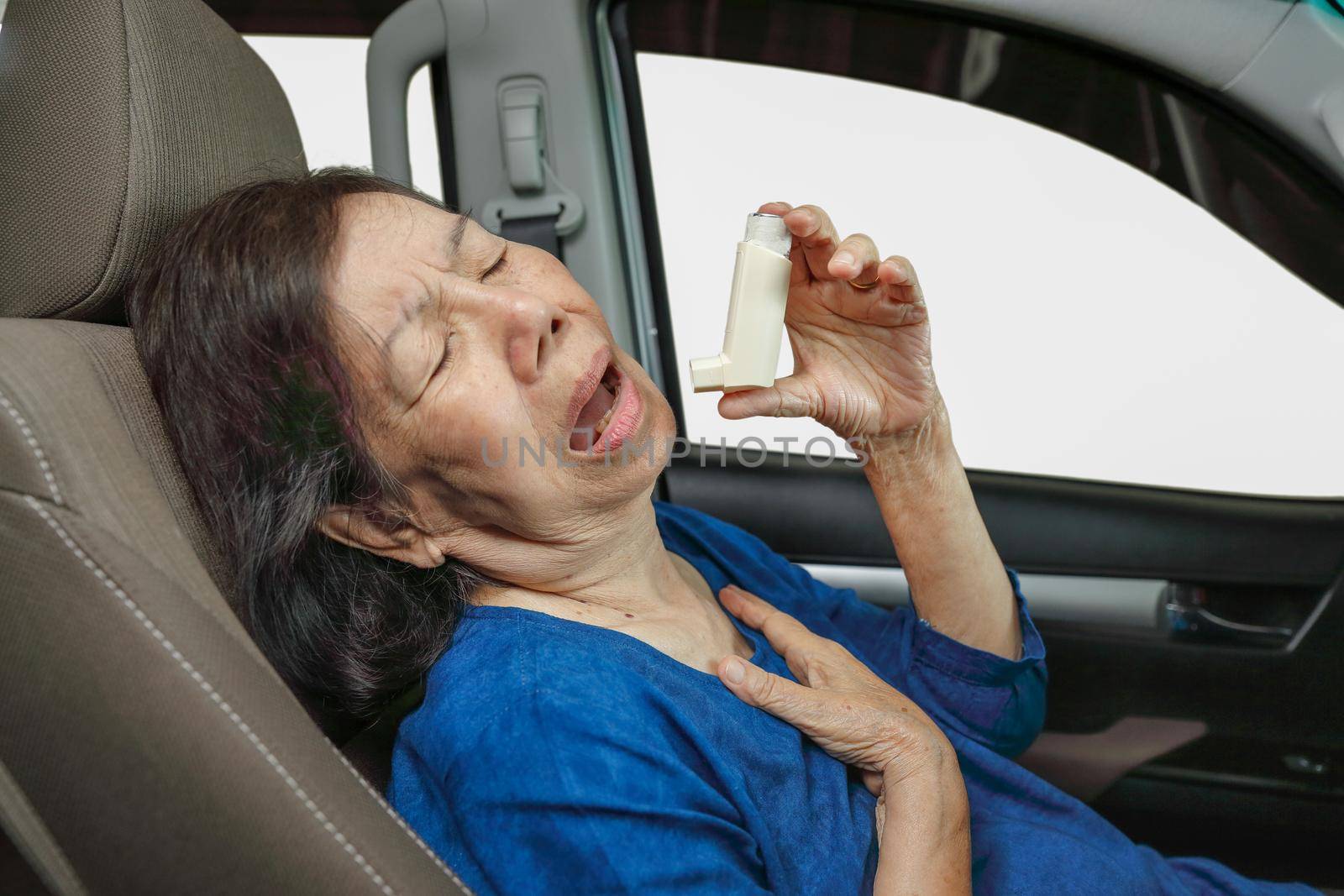 Elderly woman choking and holding an asthma spray inside car on the way