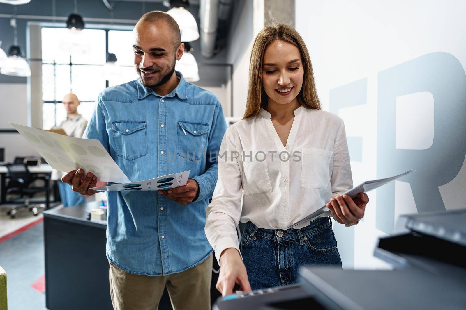 Two employees using new modern printer in office, close up