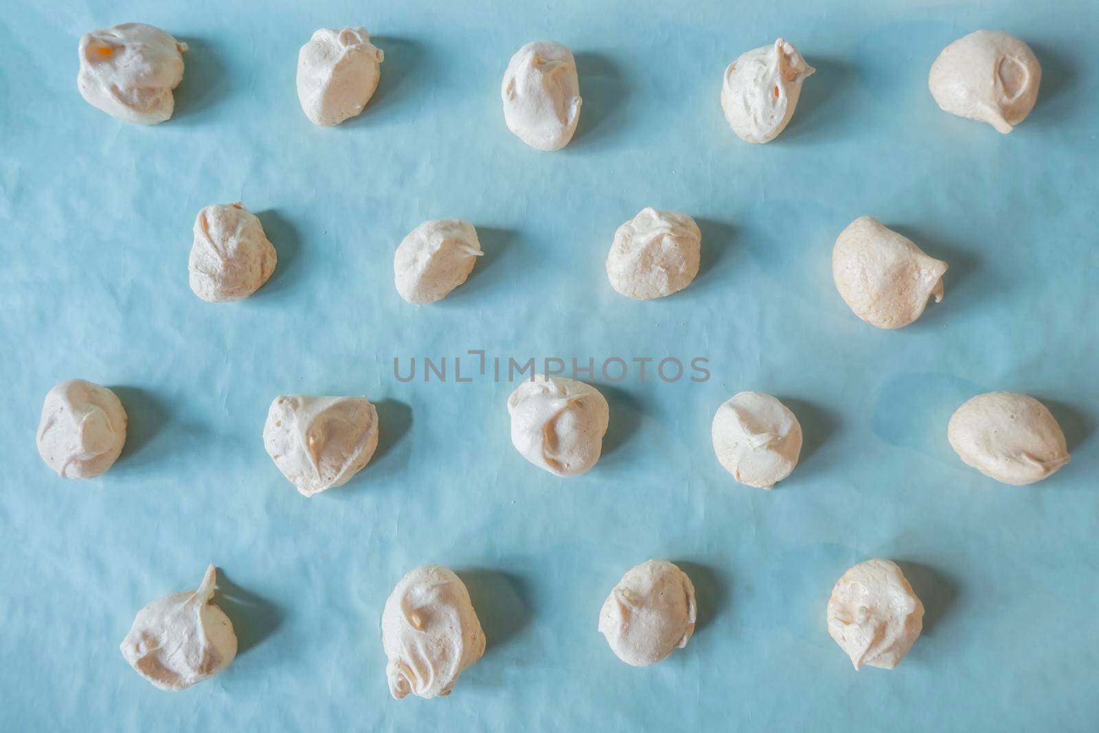Homemade french milk-colored meringues on bluet paper. flatley composition: delicious homemade meringues on craft paper