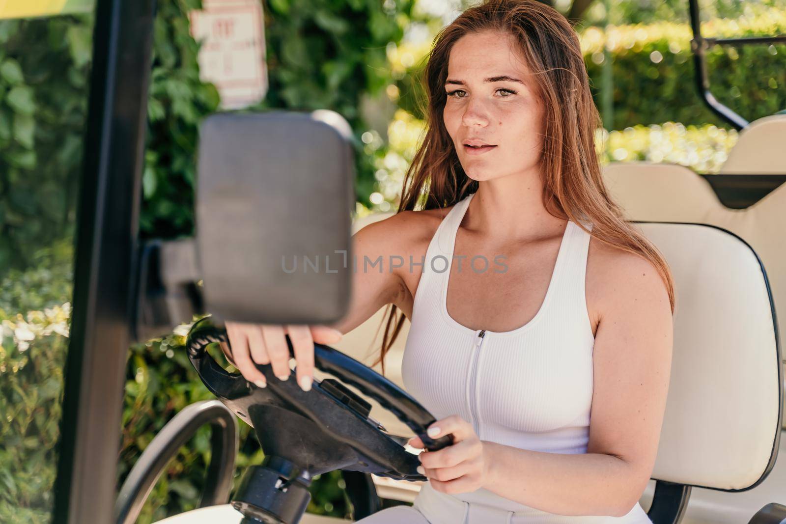 A middle-aged woman is driving a car for transporting tourists. Electric car, Tourist bus. Car for transporting people around the hotel, park, golf club.