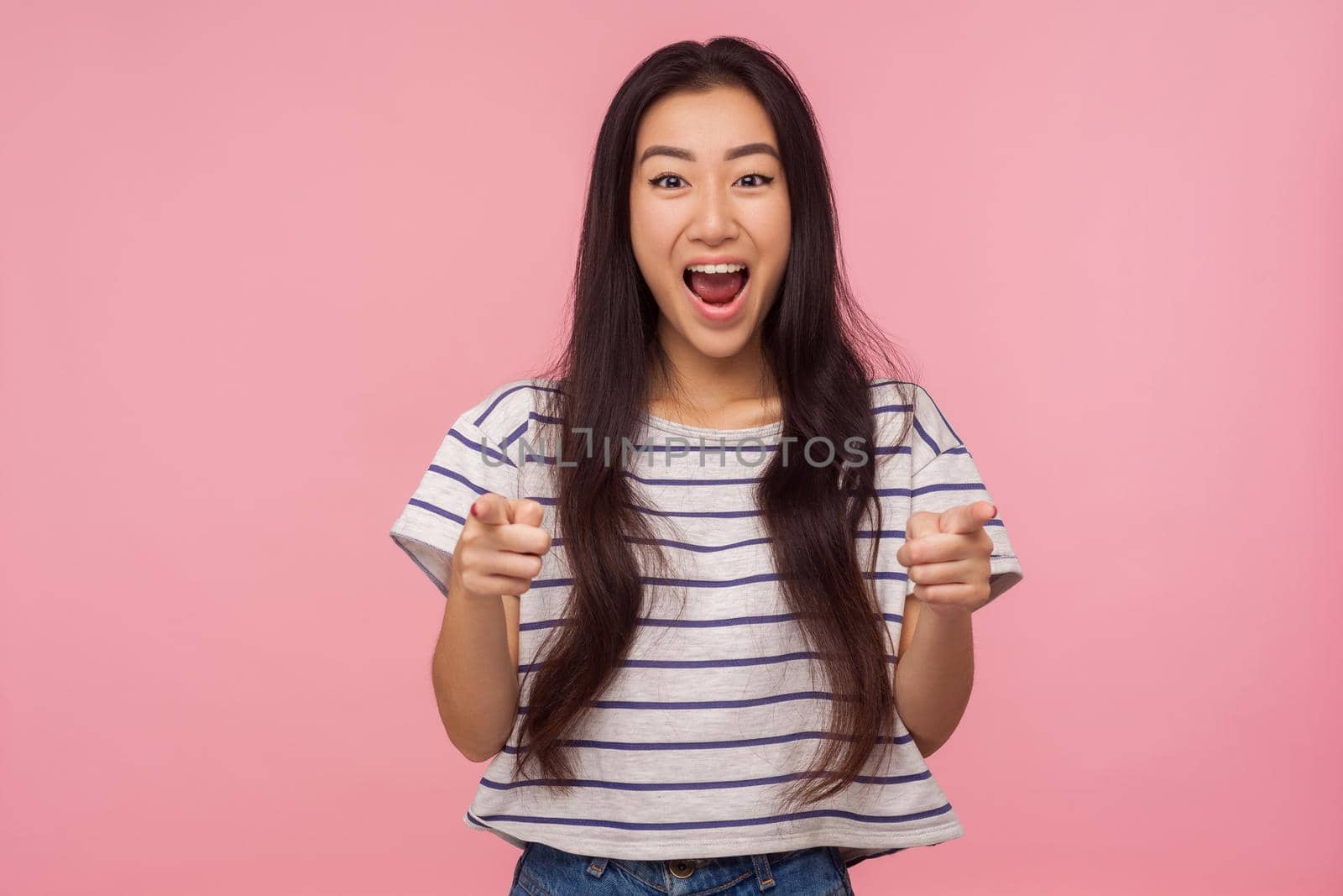 Wow, look at you, Portrait of excited shocked girl with long hair in t-shirt pointing to camera, shouting in amazement, happy and surprised about your success. studio shot isolated on pink background