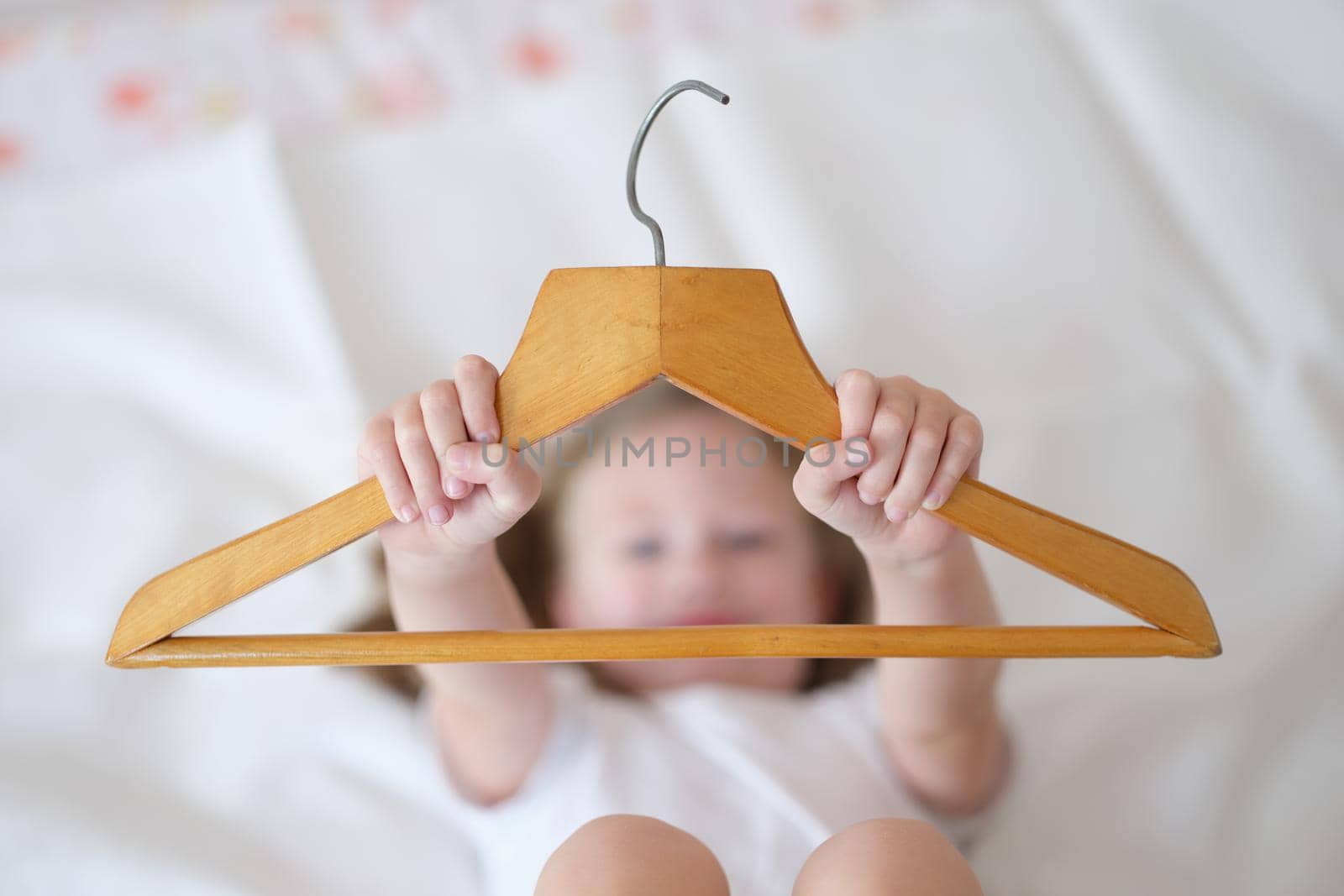 Child is holding wooden clothes hanger.