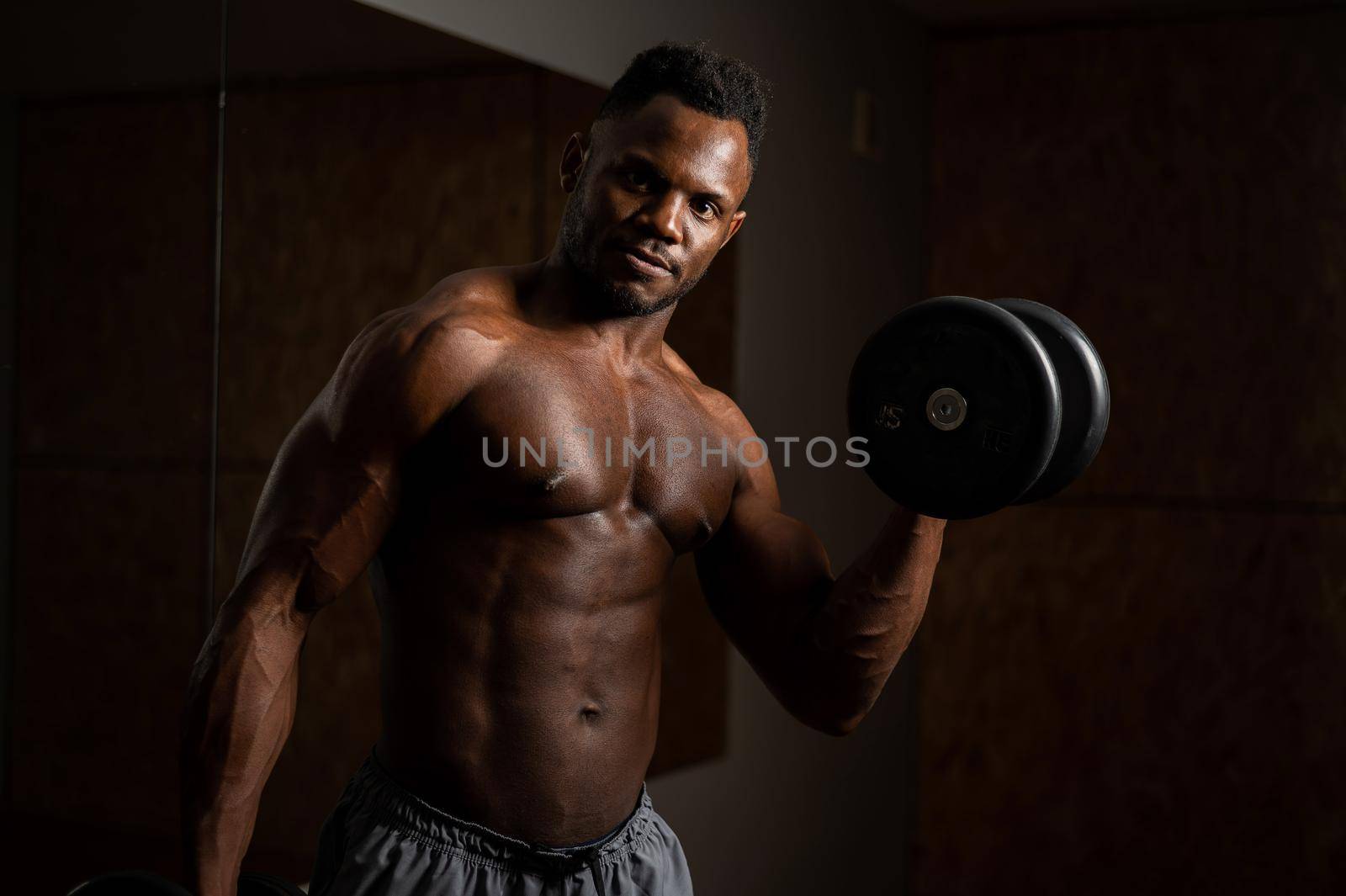 Attractive african american man doing biceps exercise with dumbbells. by mrwed54