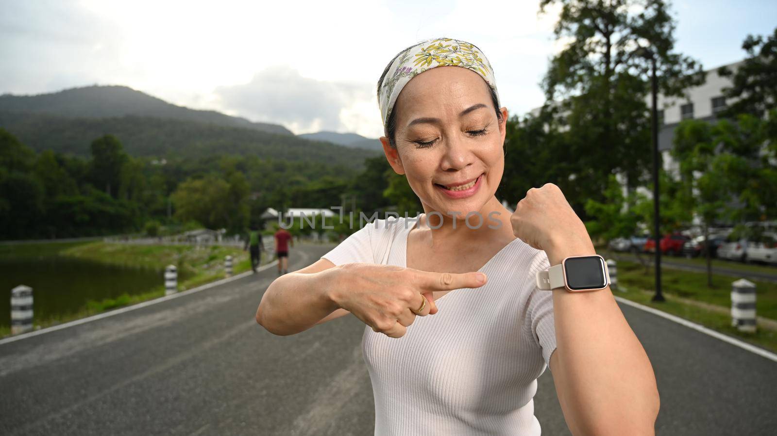 Healthy middle aged woman pointing at her smartwatch. Fitness, sport and healthy lifestyle concept.