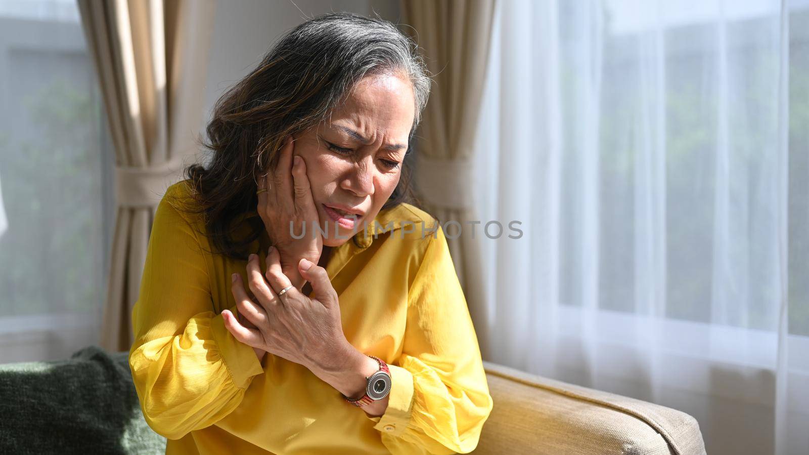 Unhappy mature woman touching sore cheek suffering from toothache cavities. Dental service help, medical insurance concept.