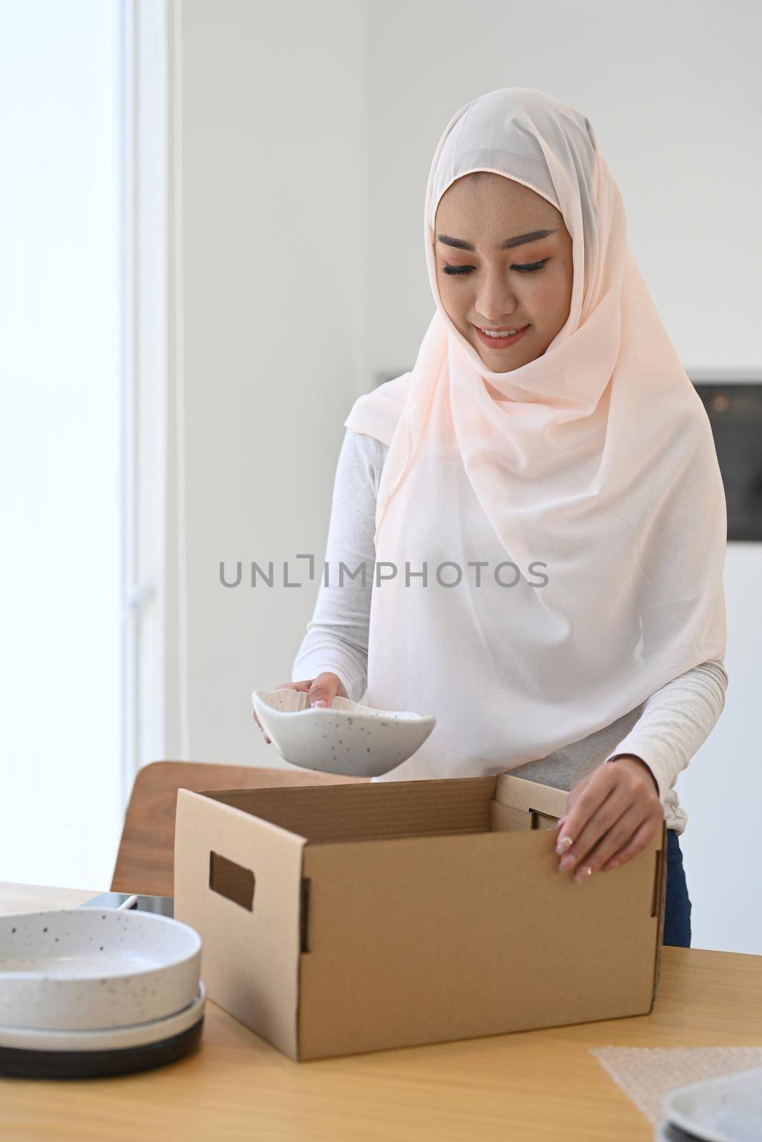 Muslim woman small business owner packing product in cardboard box for shipment. E-commerce, Online selling concept.
