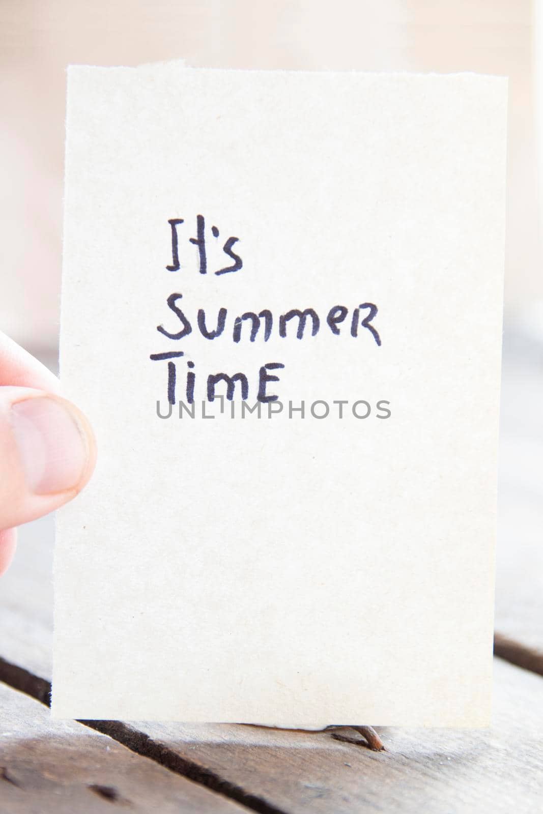 It's summer time creative concept. The hand holds a sign with the inscription.