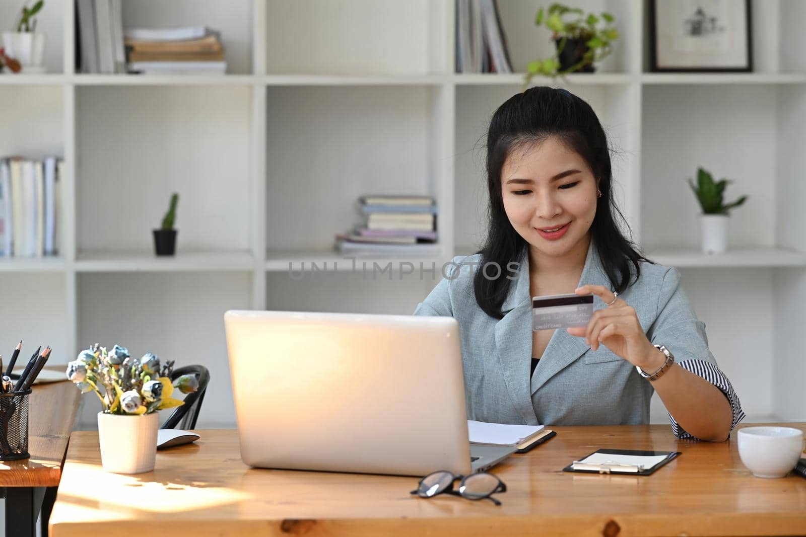 Pretty young asian woman making payment online or baking online with computer laptop.