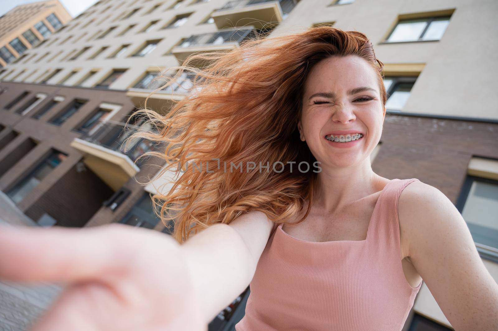 Beautiful young red-haired woman with braces on her teeth smiling in the summer outdoors by mrwed54