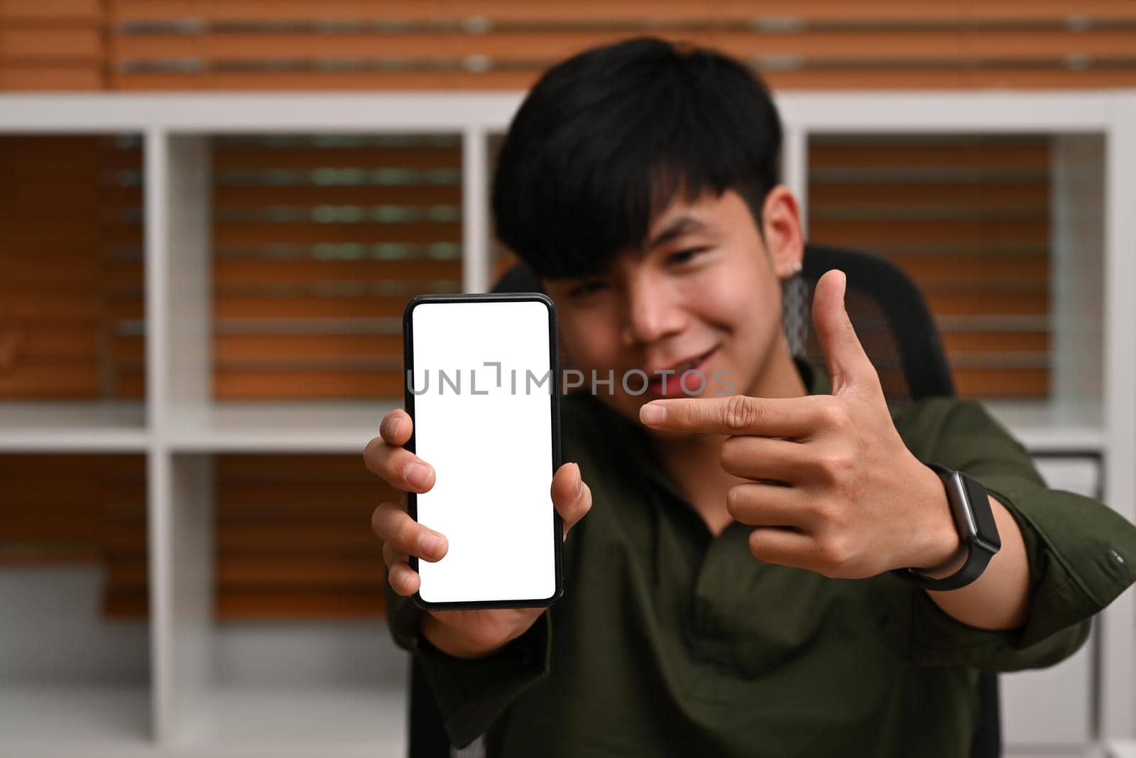 Handsome asian man holding and showing smart phone with blank screen for advertise. by prathanchorruangsak