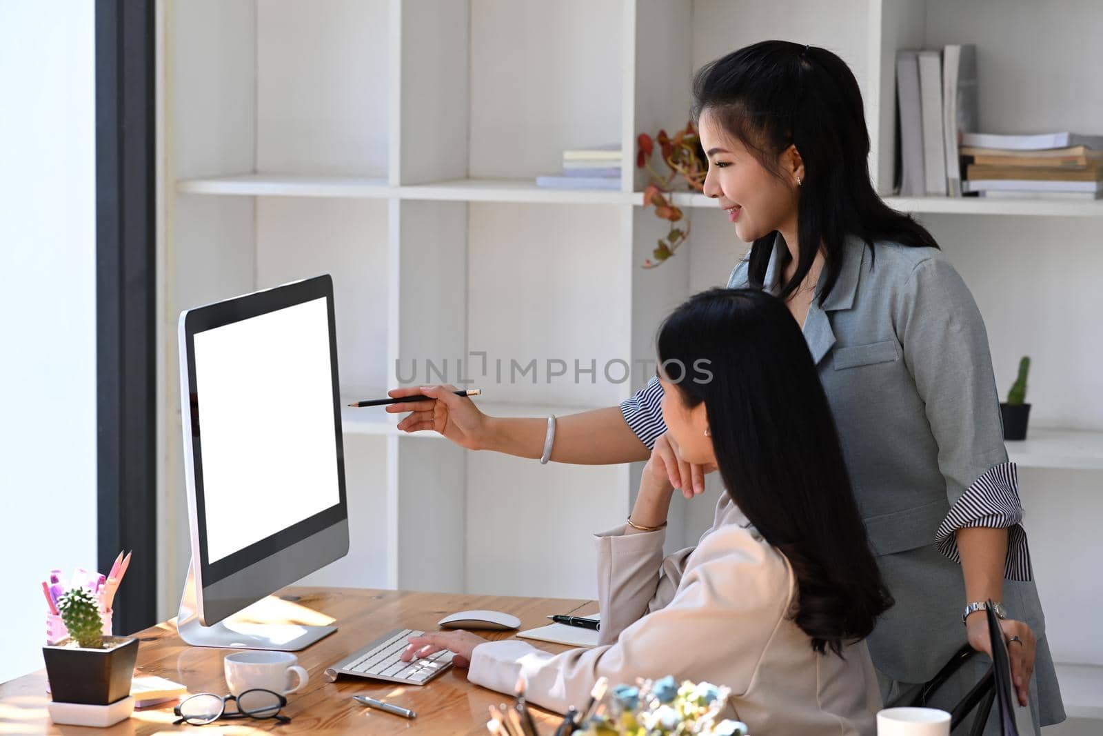 Two businesswomen brainstorming and analyzing financial data on computer.