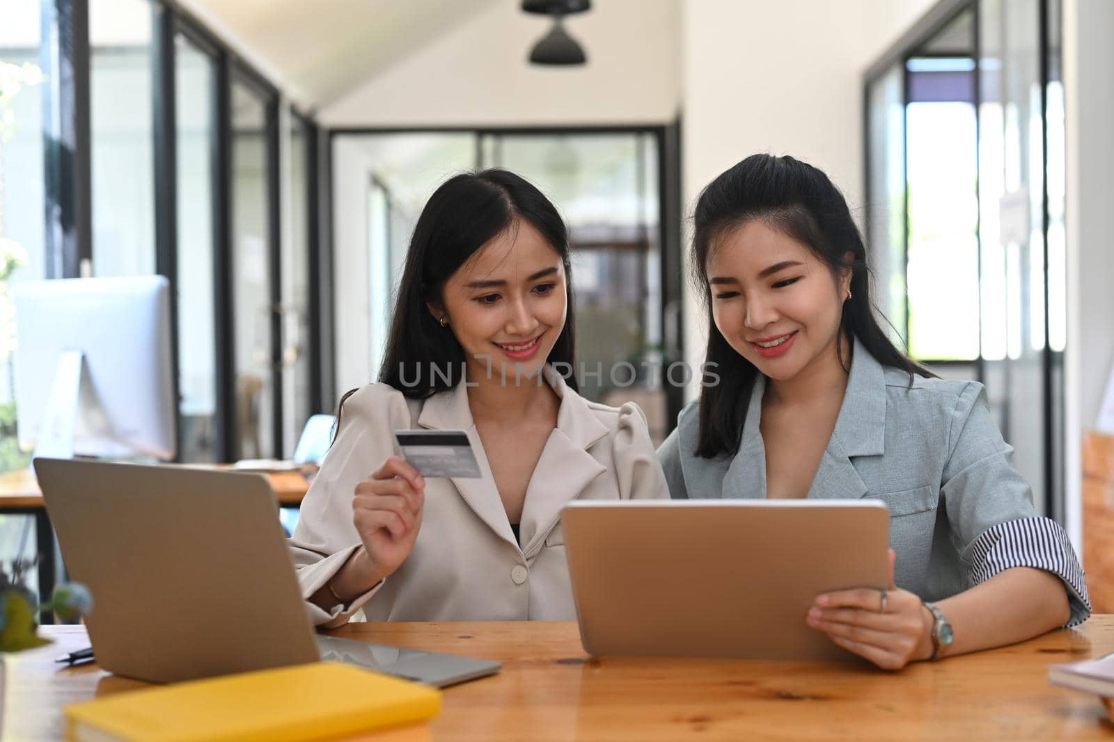 Two smiling young asian woman shopping online with digital tablet together.