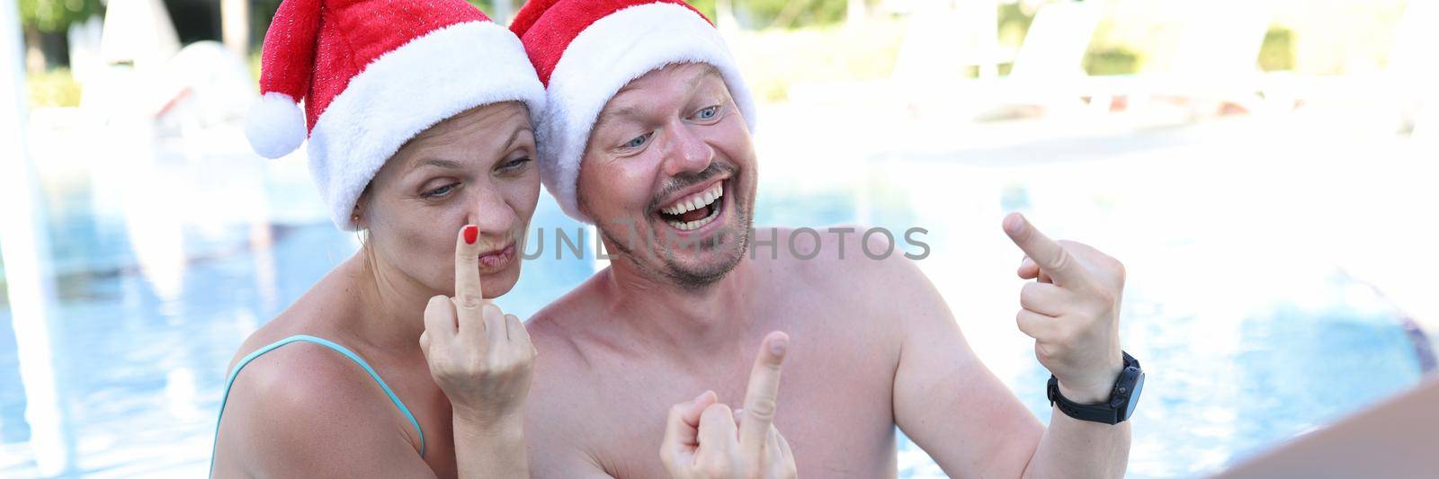 Man and woman in santa claus hats show fucking gesture into monitor by kuprevich
