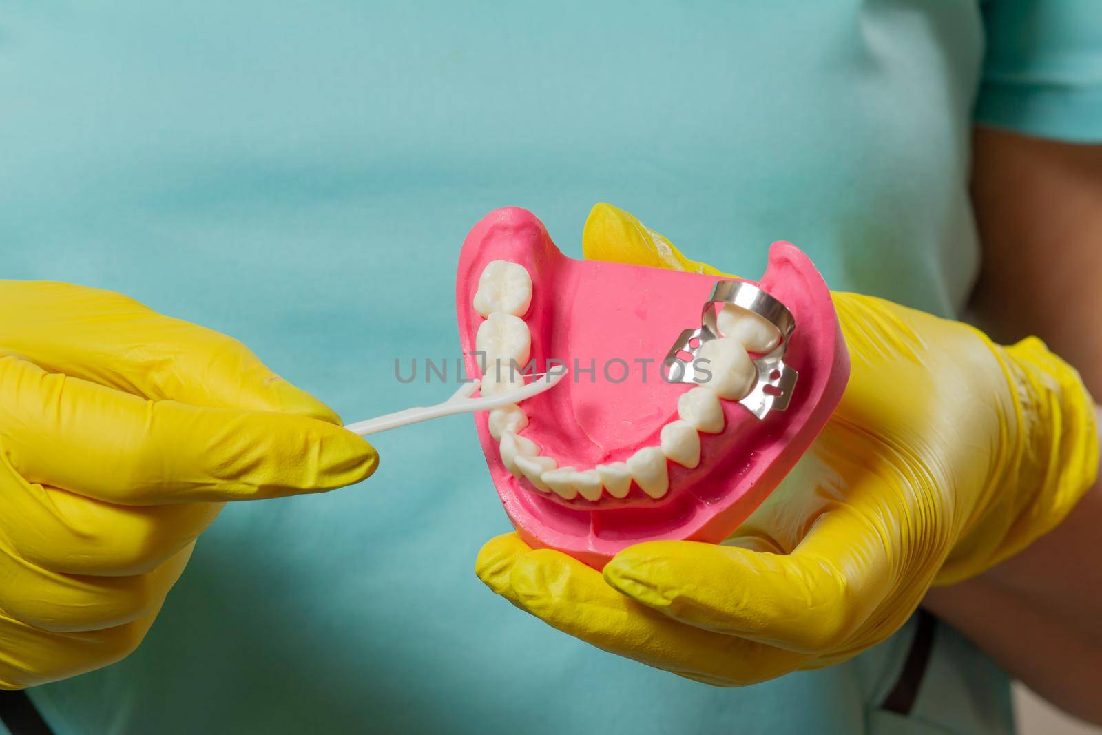 Close-up view of hands with a human jaw layout and a floss toothpick.