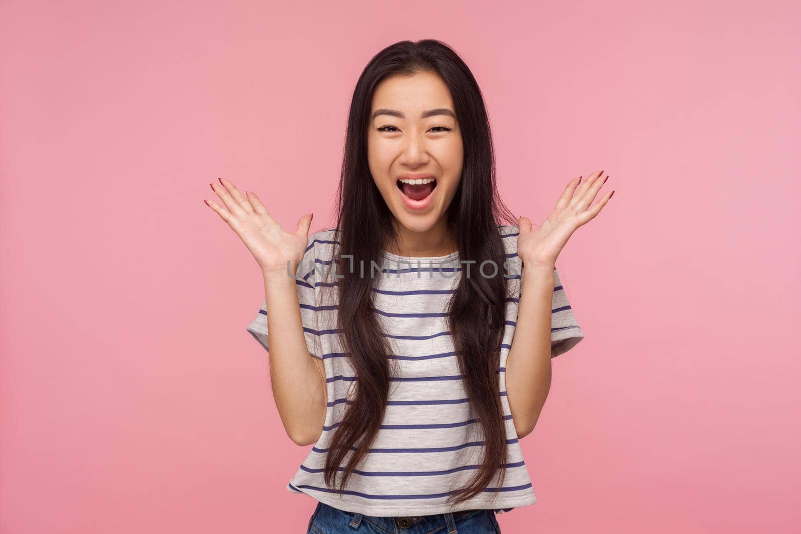 Wow, I won, Portrait of surprised happy girl with long hair in striped t-shirt screaming in amazement, looking shocked and rejoicing unexpected victory. indoor studio shot isolated on pink background