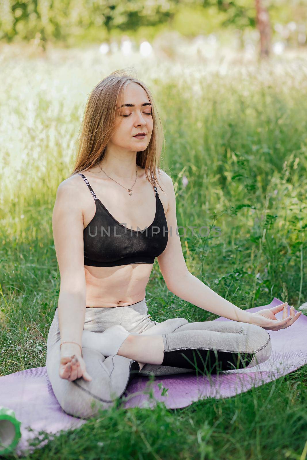 Yoga woman on green grass girl relaxes in the field. Yoga woman in green park girl doing gymnastics outdoors. Meditating woman in meditation in yoga pose practices outdoors