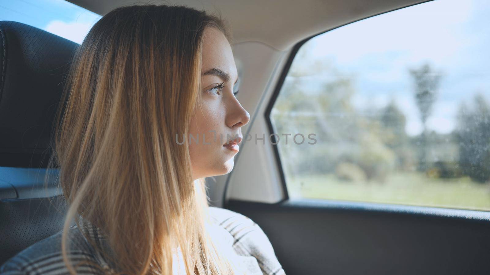 A young girl rides in a car in the back seat