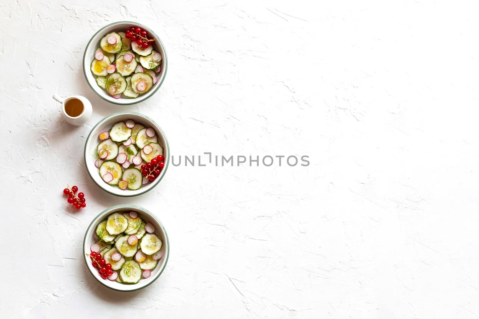 radish and cucumber salad served in a three small round bowls in a row, top view, copy space