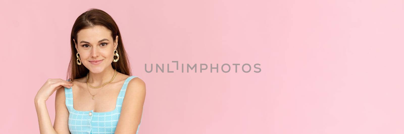 Attractive dark-haired girl in a bright summer outfit smiles with copy space. Positive smiling woman posing on pink background. Web banner.