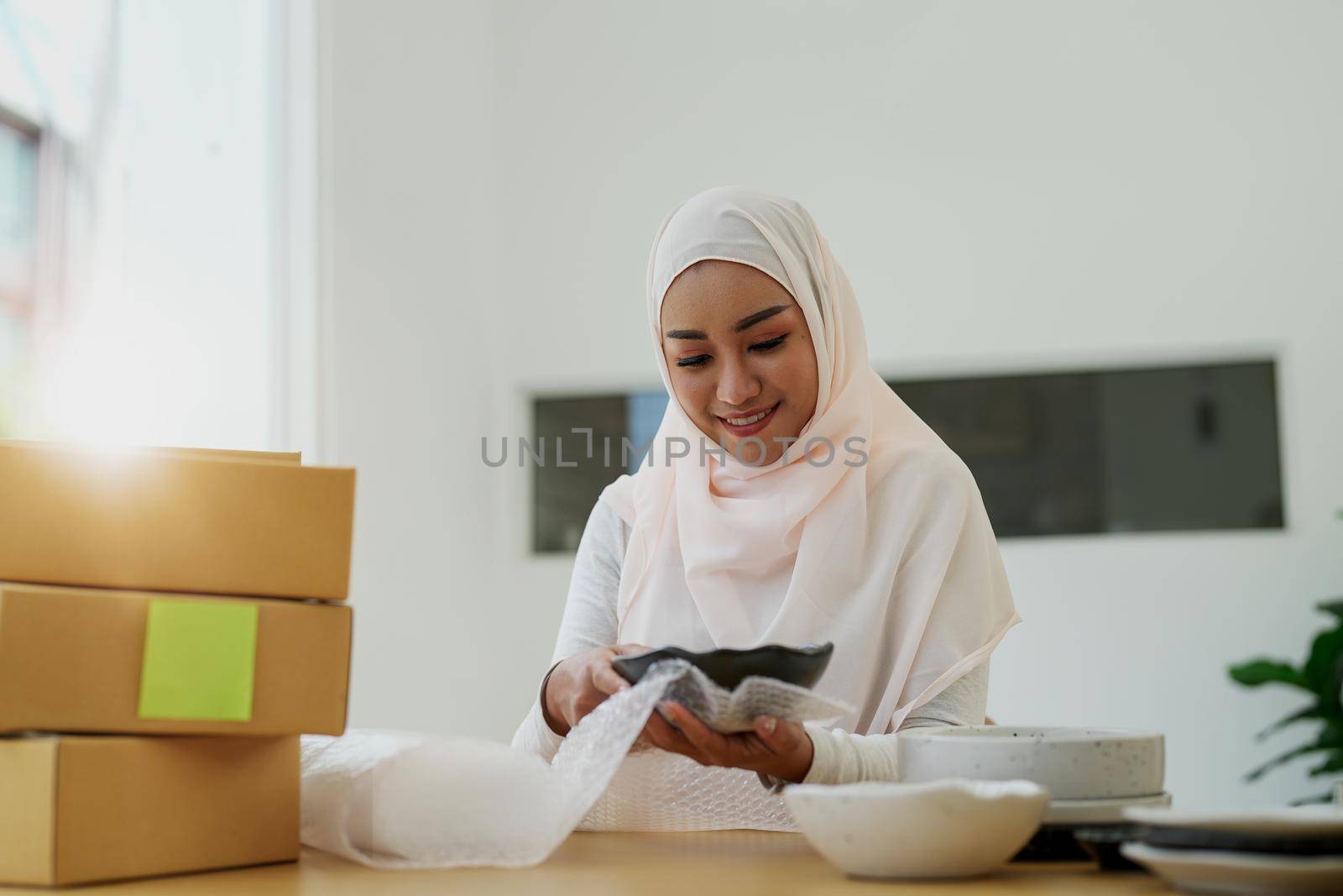 Asian muslim owner packing products preparing toshopping and make arrangements for delivery online while he works at home