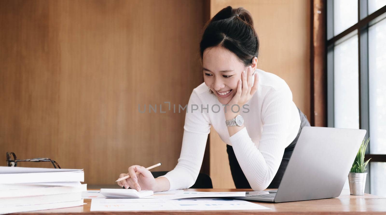 Portrait of Young Asian woman hand freelancer is working her job on computer tablet in modern office. Doing accounting analysis report real estate investment data, Financial and tax systems concept..