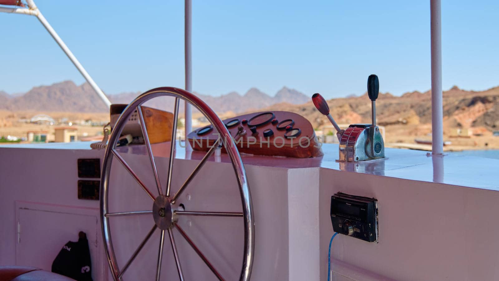 Captain's cabin, steering wheel and mountain view.