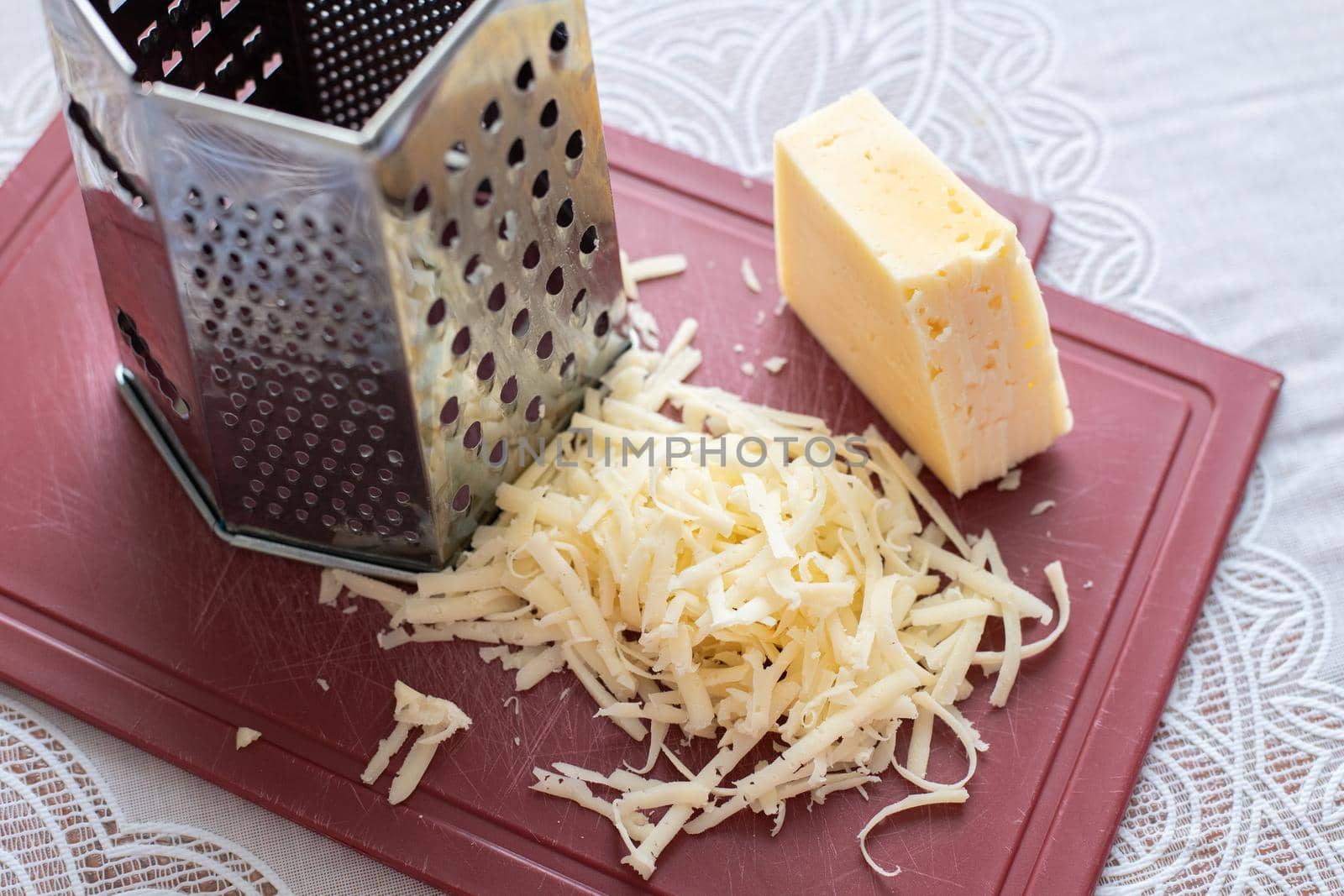 A pile of grated cheese on a plastic board next to a grater