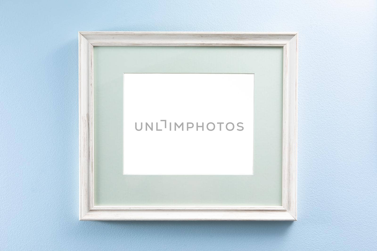 wooden picture frame with passe-partout on a blue wall, copy-space background