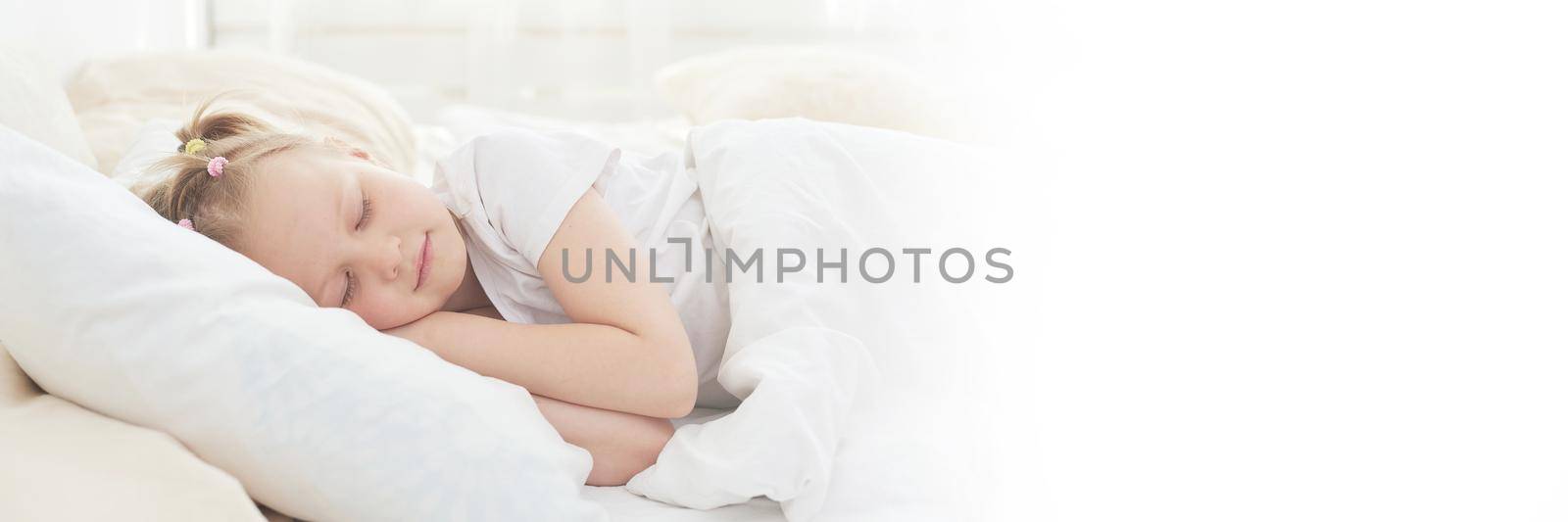 A cute little girl enjoys an afternoon nap in bed after dinner. Web banner.