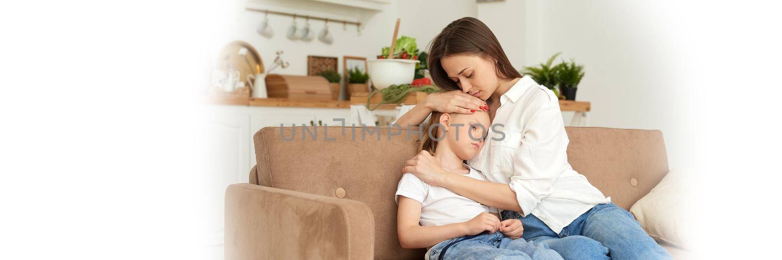 A young mother supports her daughter, calms her down and strokes her head. Little girl crying and complaining to her mother on the couch at home. Web banner